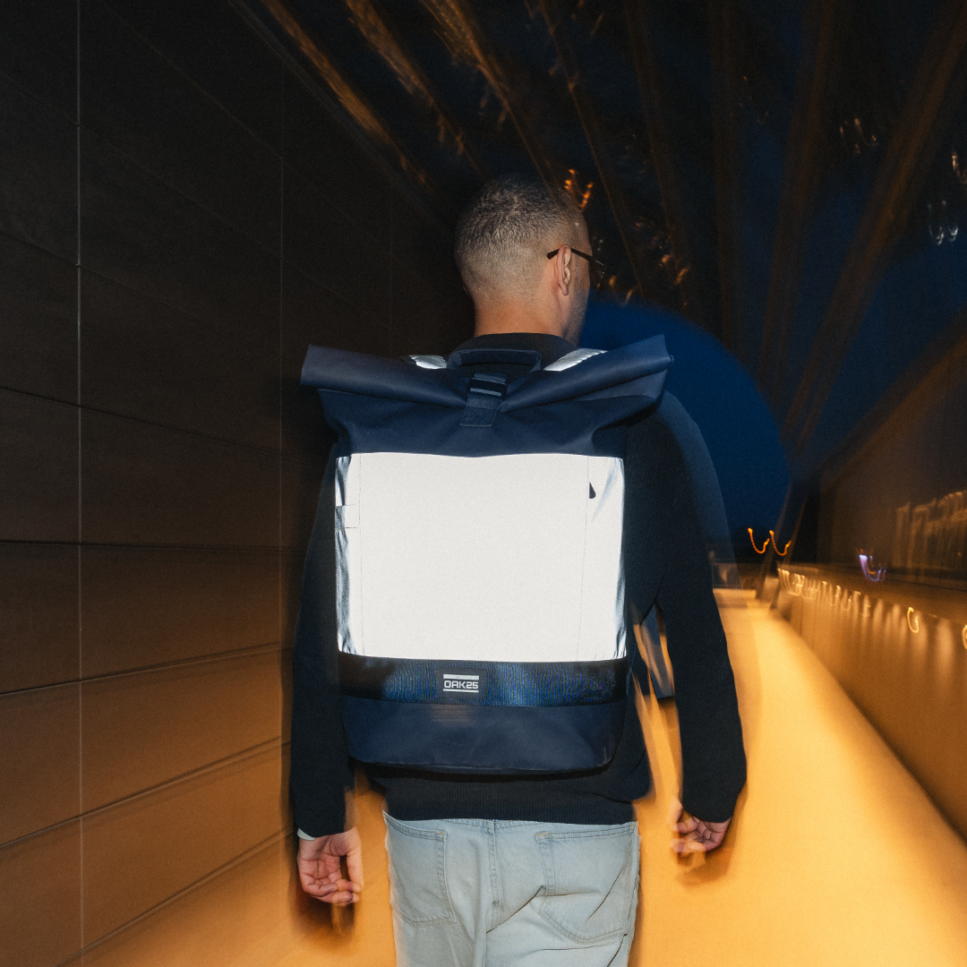 Mann trägt nachts reflektierenden navyblauen Rolltop-Fahrradrucksack von OAK25