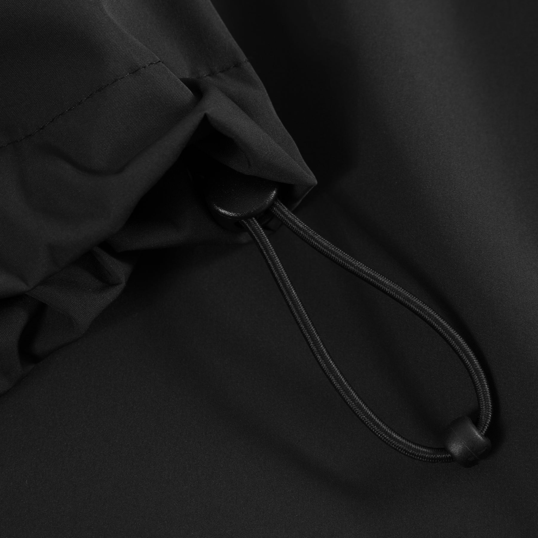 Schwarzer Kordelzug mit Stopper an einem Windbreaker mit verstellbarer Kapuze