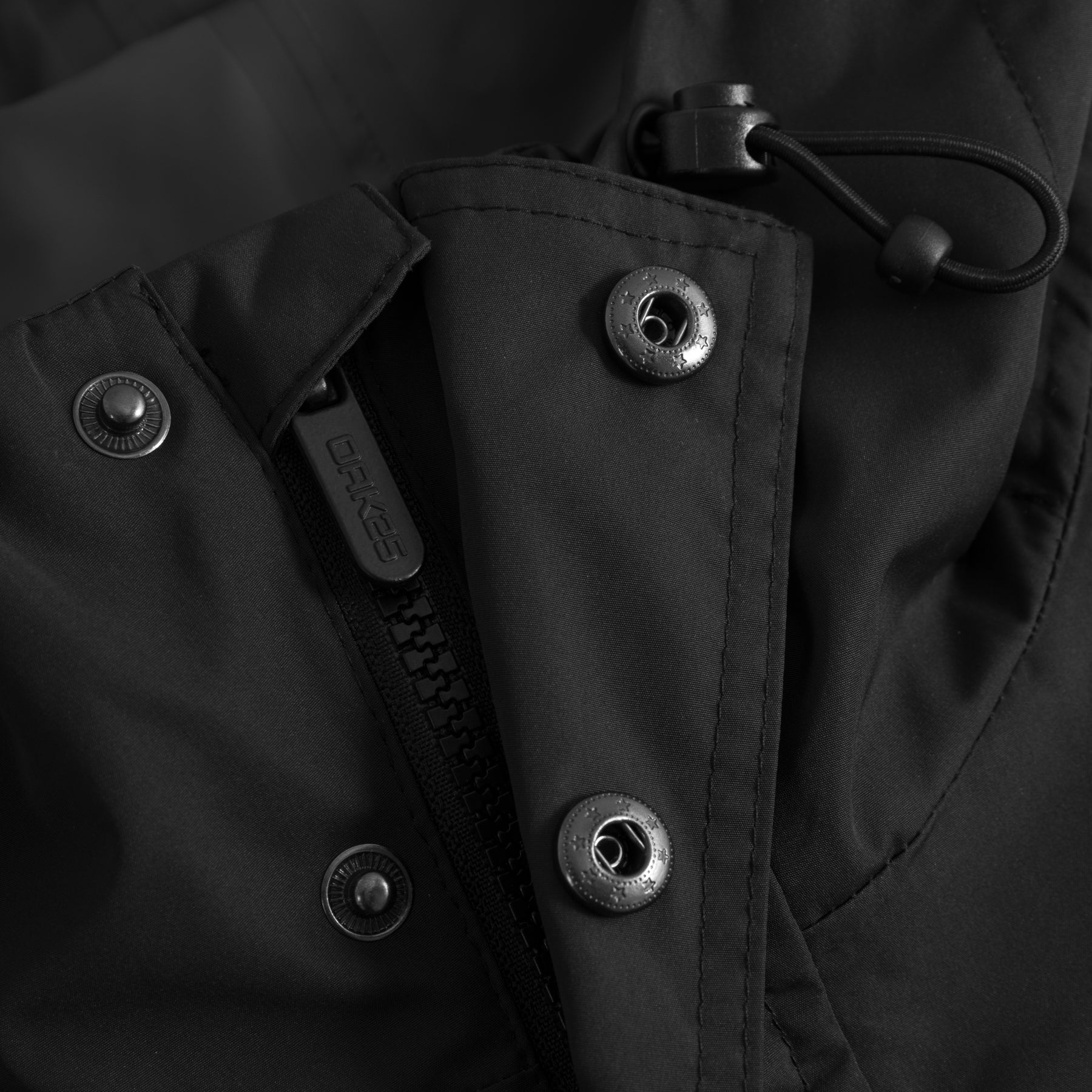 Schwarzer Windbreaker mit verschweißten Nähten, Schwerpunkt auf Reißverschluss und Druckknöpfen