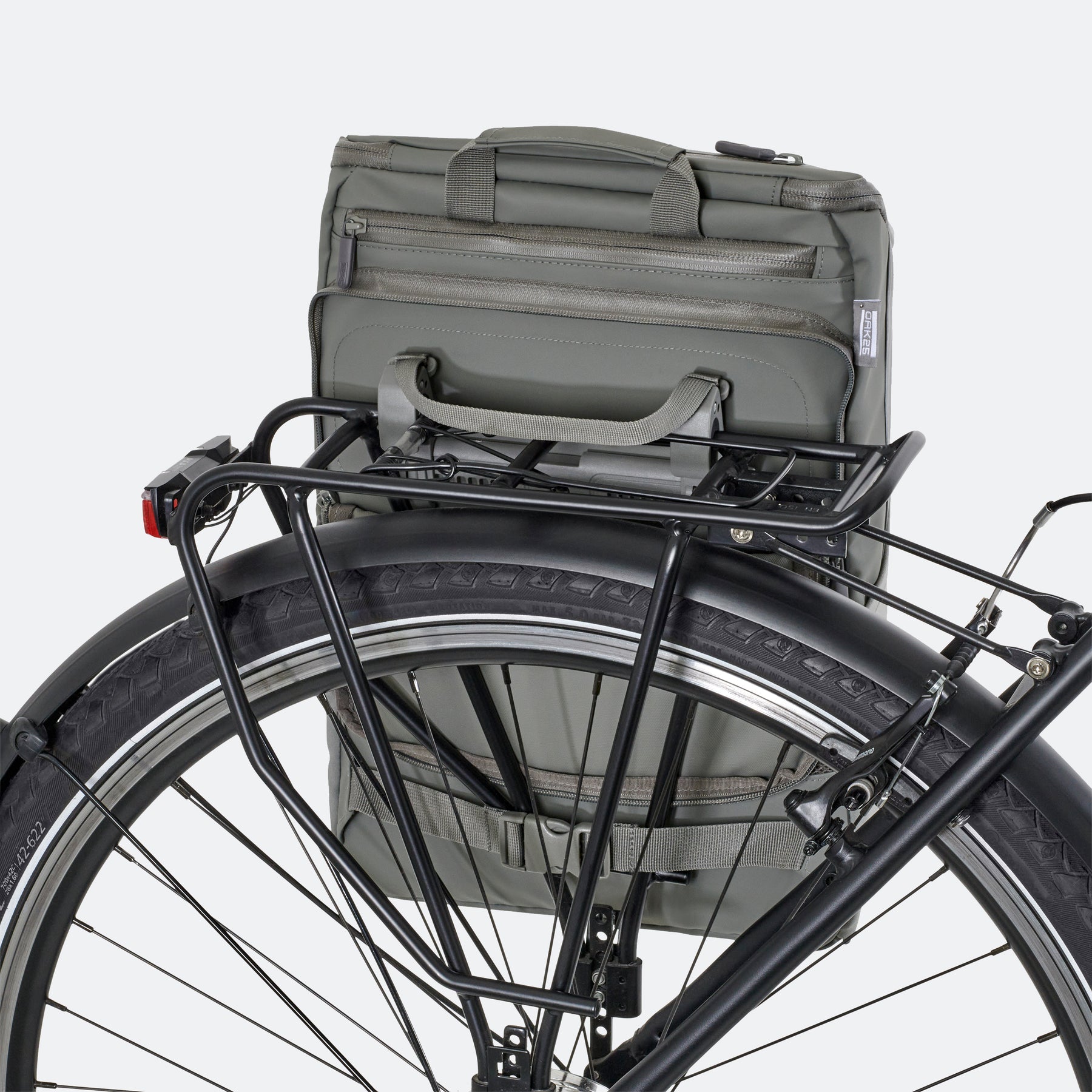 Salbeigrüne OAK25 Daybag Fahrradtasche befestigt an schwarzem Gepäckträger hinter Fahrradreifen