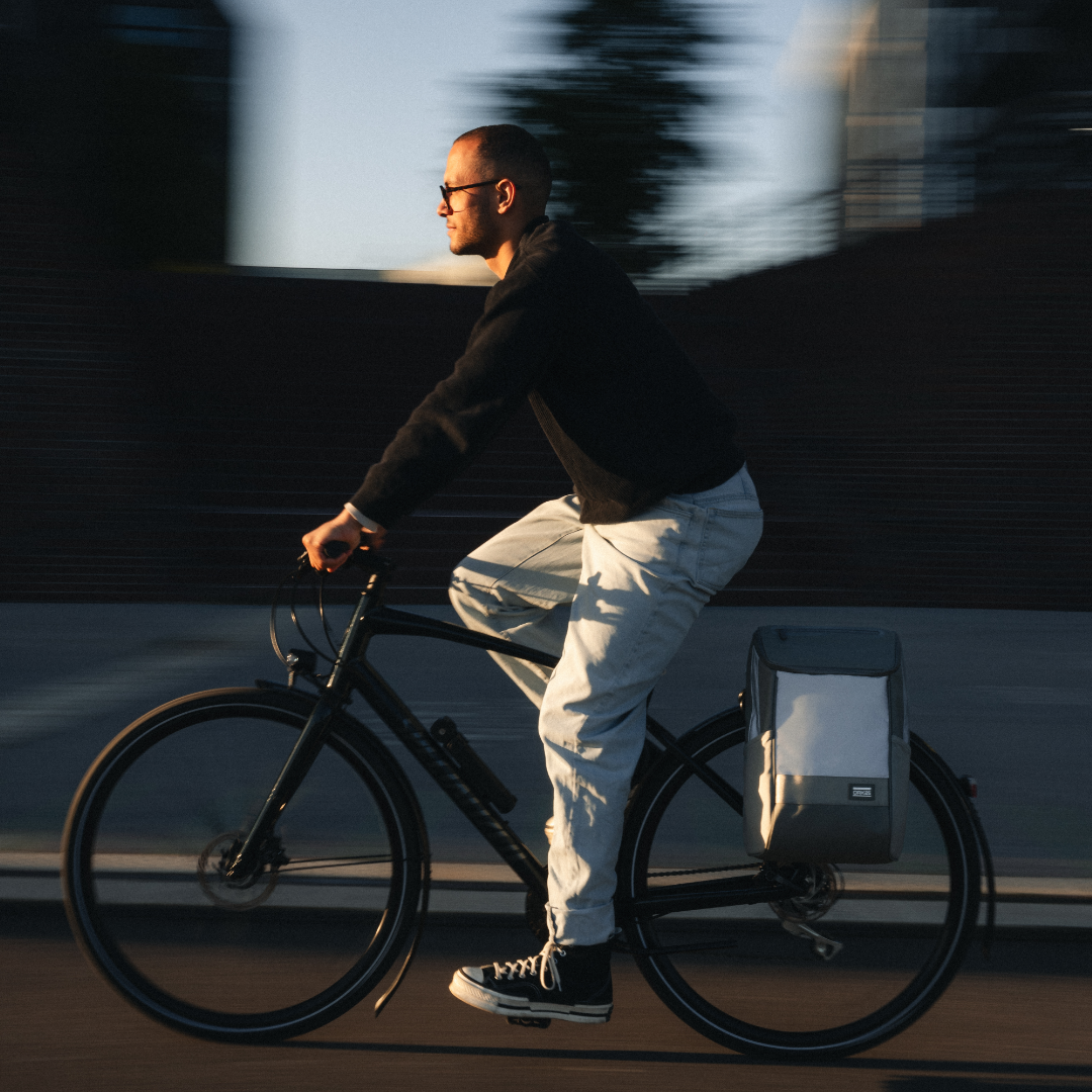 Mann fährt Fahrrad mit salbeigrüner reflektierender Fahrradtasche am Gepäckträger