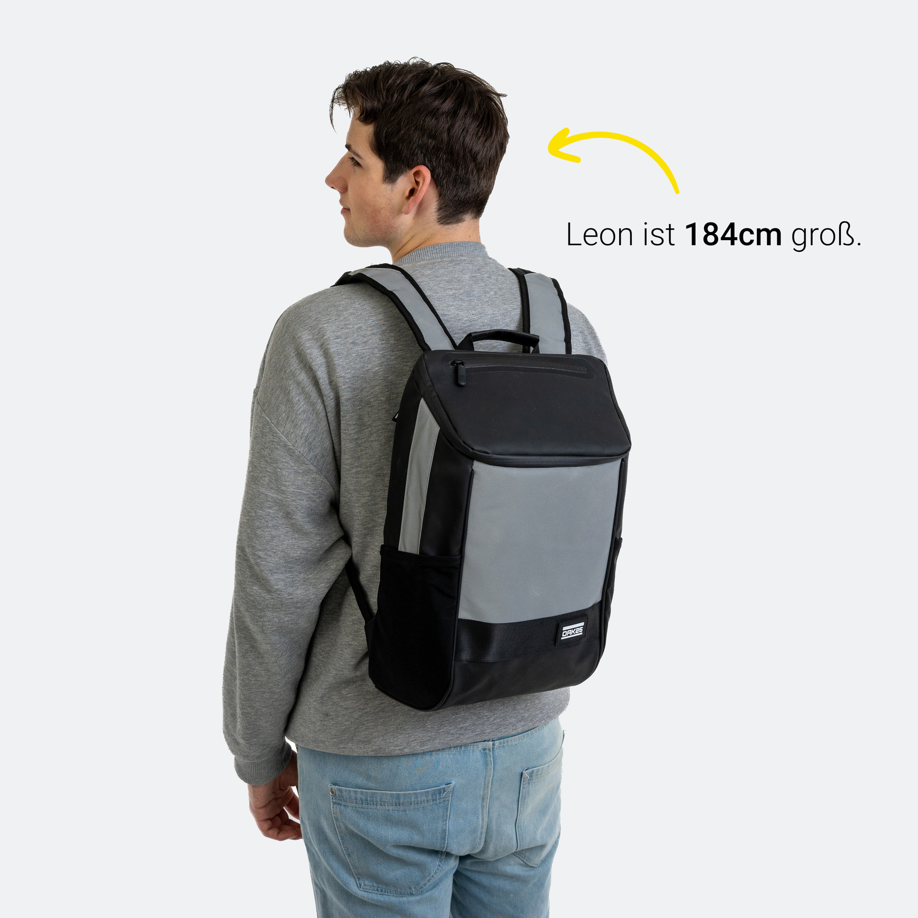 Junge mit 184 cm Größe trägt schwarzen Daybag-Rucksack mit reflektierenden grauen Flächen