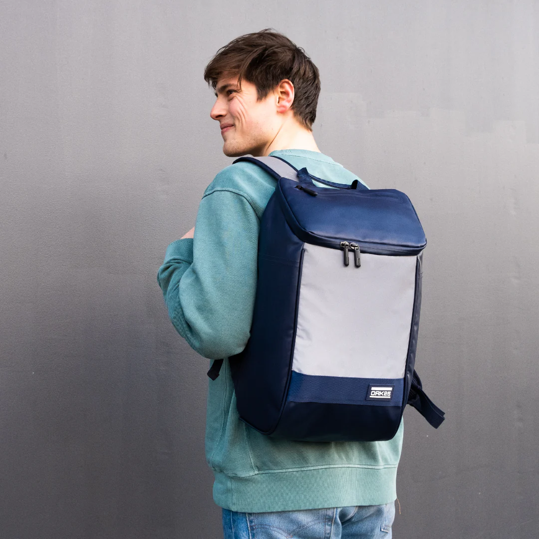 Mann trägt navyblauen Daybag mit reflektierender Vorderseite und OAK25-Logo auf dem Rücken