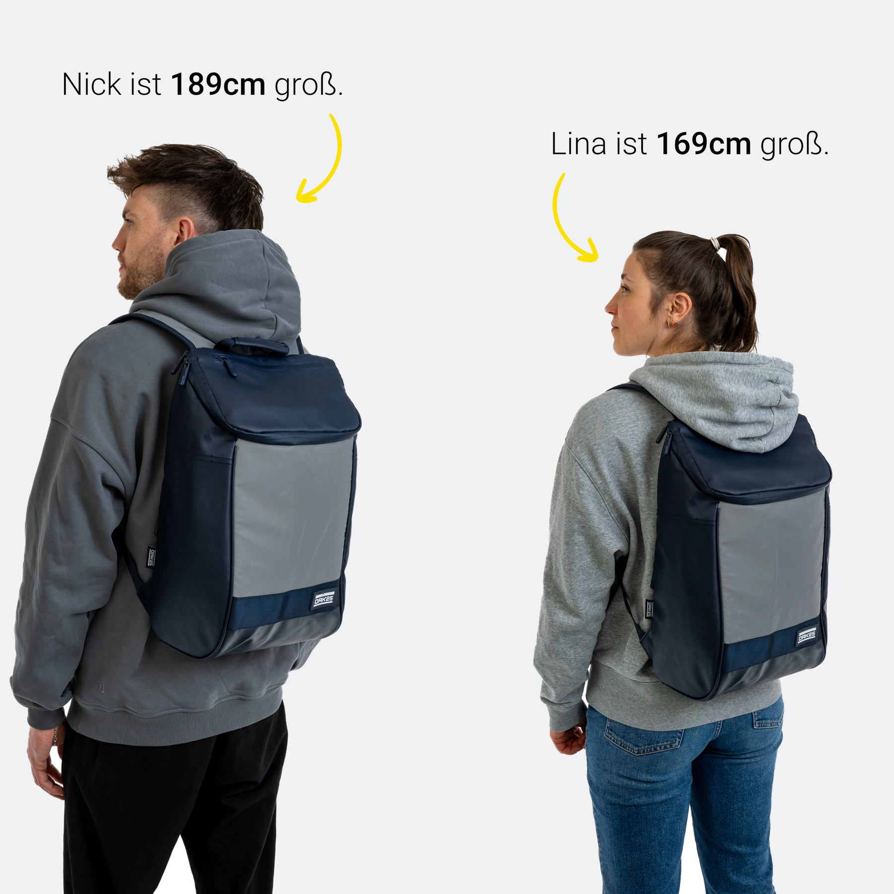 Zwei Personen tragen einen navyblauen und reflektierenden Daybag-Rucksack, links 189 cm groß, rechts 169 cm groß