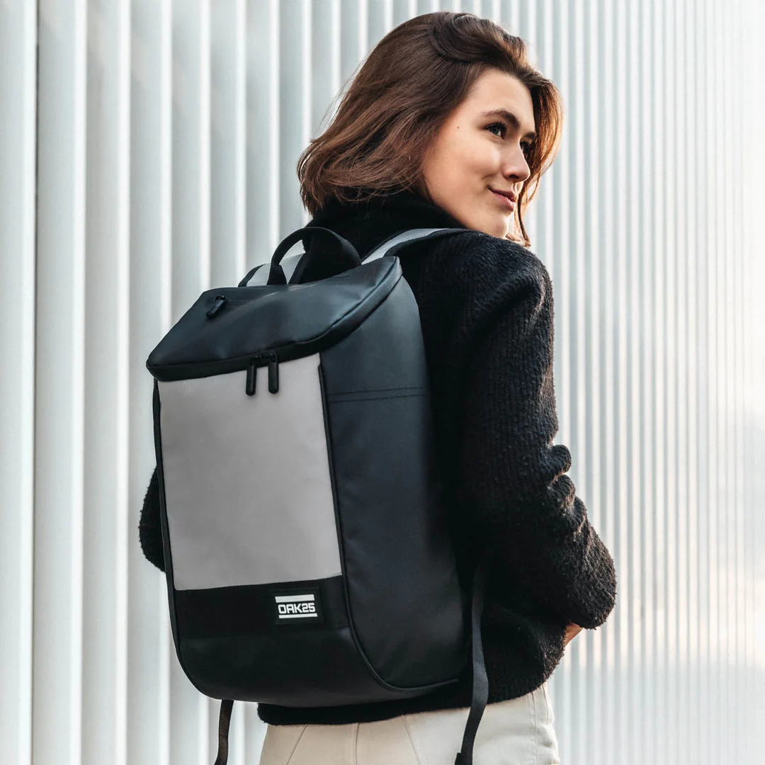Frau trägt schwarze OAK25 Daybag mit reflektierender grauer Tasche Rückenansicht