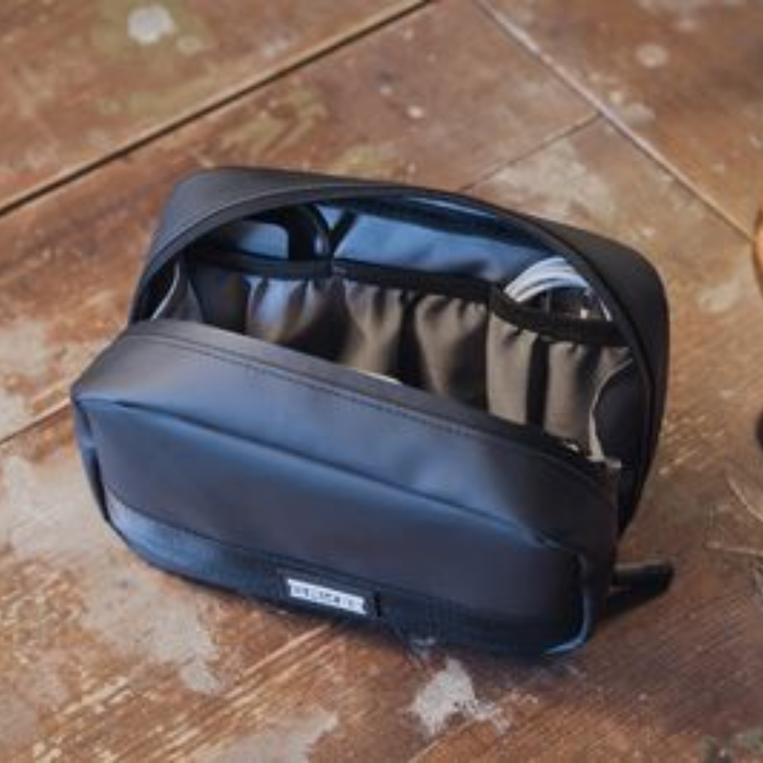 Schwarze Kabeltasche mit mehreren Fächern und Kabeln auf hölzernem Untergrund