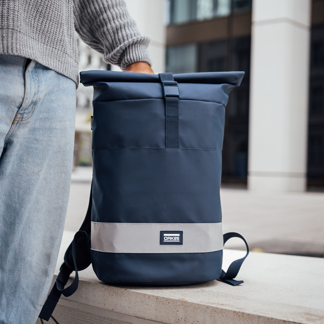 Dunkelblauer OAK25 Rolltop-Rucksack mit reflektierendem Streifen und Logo auf hellem Untergrund
