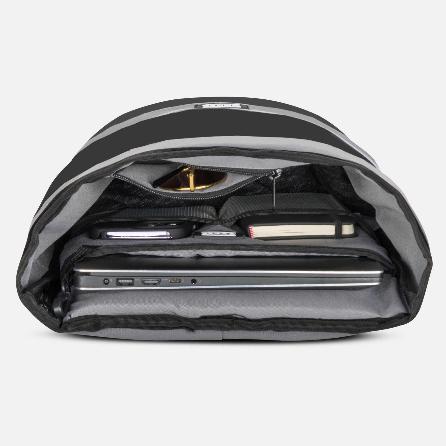 Schwarzer Rolltop-Rucksack geöffnet mit Laptop, Notizbuch, Smartphone und Sonnenbrille in Innenfächern