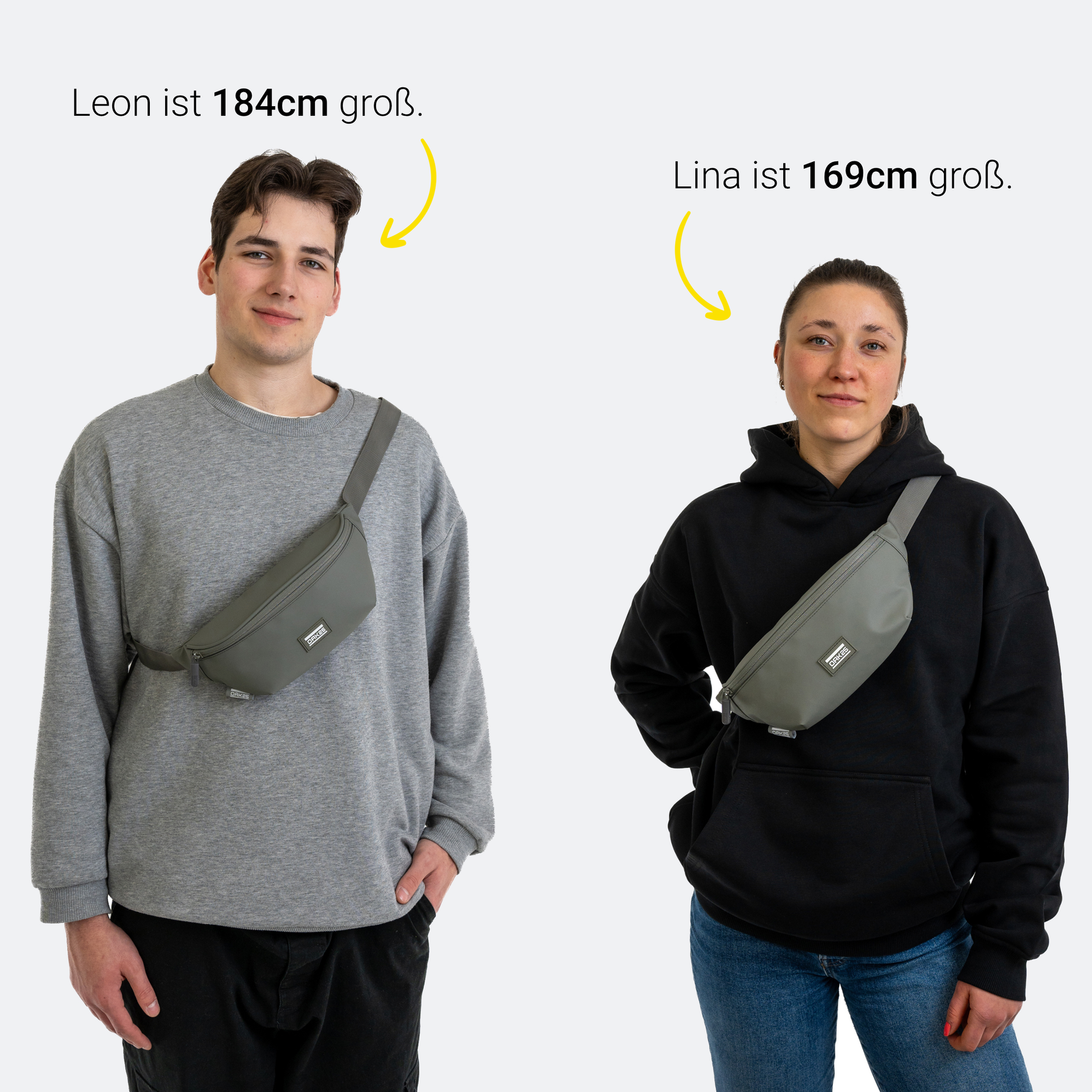 Zwei Personen tragen salbeigrüne Gürteltaschen. Leon ist 184 cm groß und trägt graues Sweatshirt, Lina ist 169 cm groß und trägt schwarzen Hoodie.