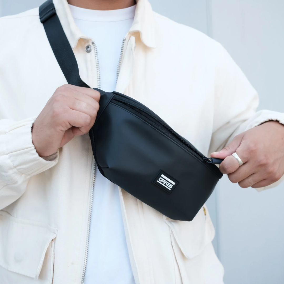 Schwarze Bauchtasche von OAK25 aus glattem Material mit Reißverschluss, getragen über der Schulter