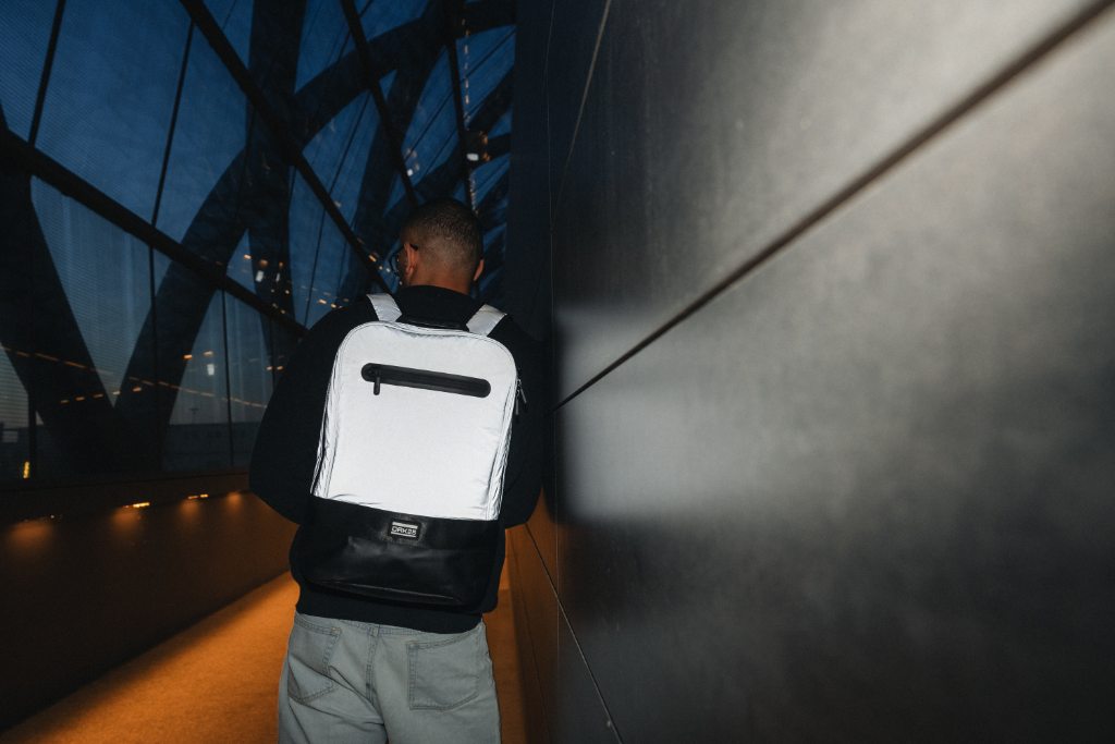 Mann mit reflektierendem weißen Rucksack in dunklem, modernem Gang