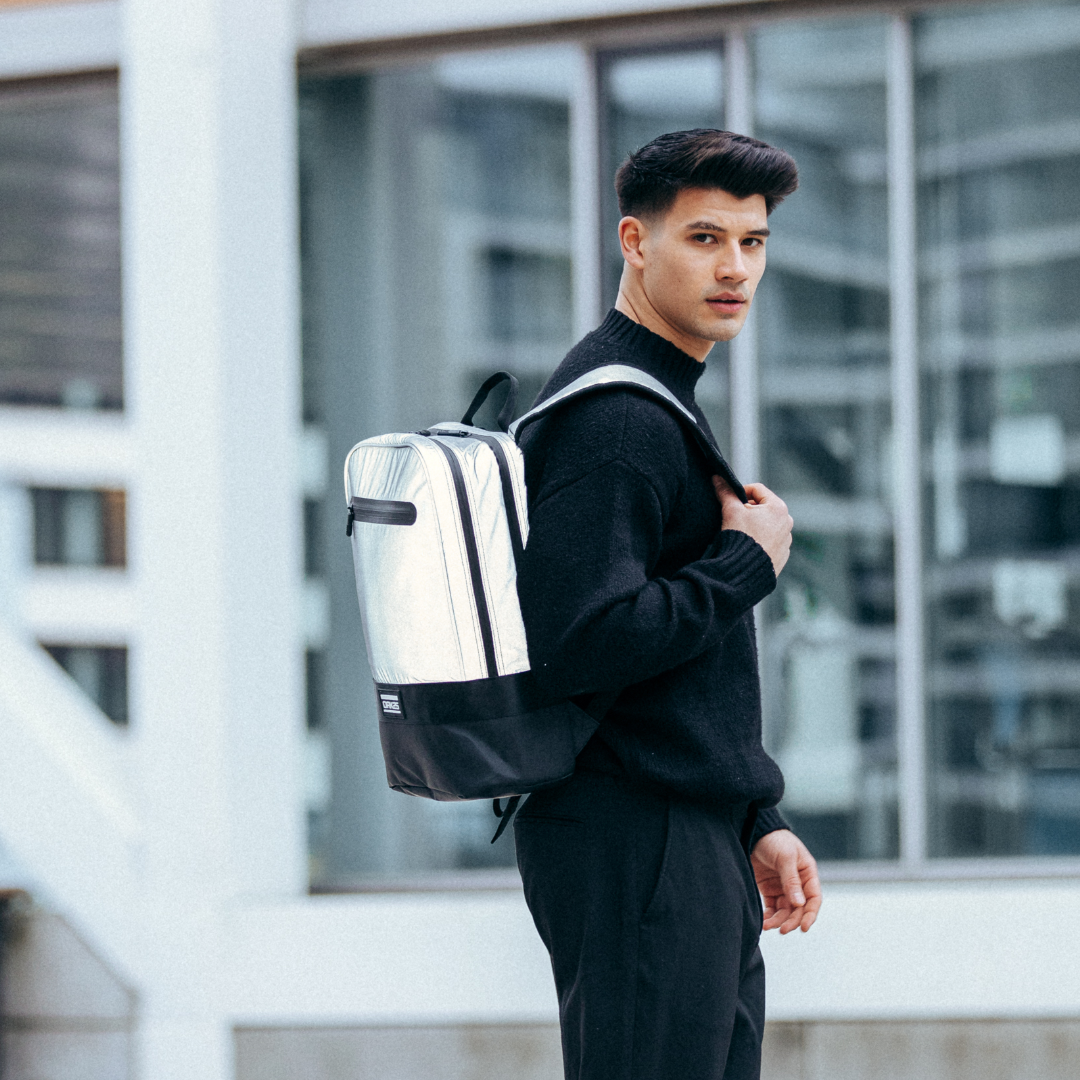 Junger Mann trägt silber-schwarzen, reflektierenden Office-Rucksack