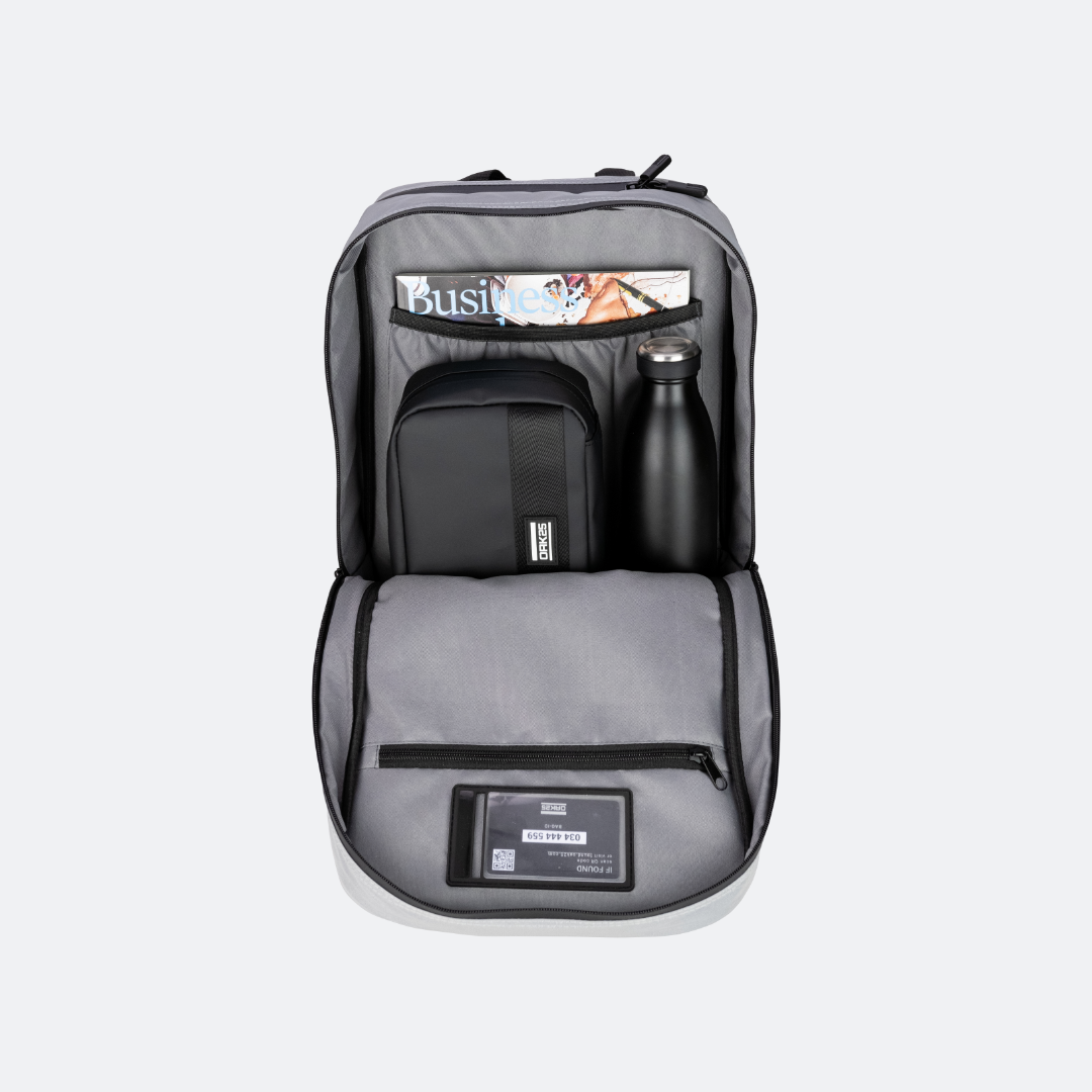 Offenes schwarzes Rucksack-Hauptfach mit Zeitschrift, kleinem schwarzen Täschchen, Metallflasche und Sichtfenster mit Ausweis