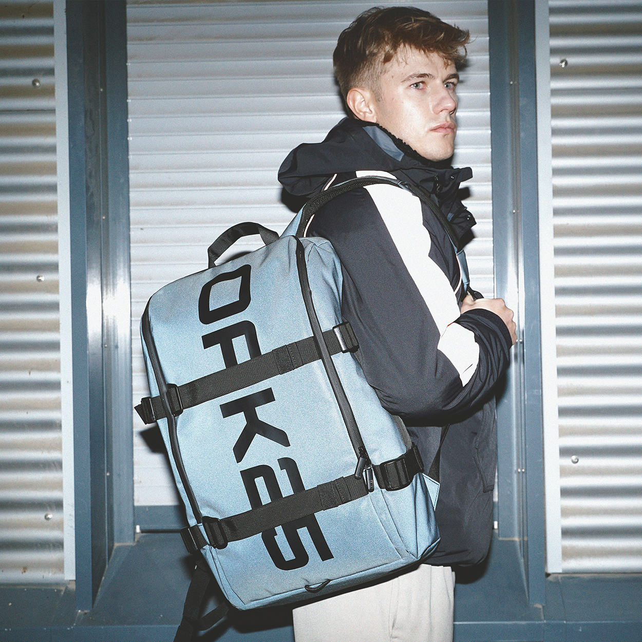 Mann trägt hellblauen OAK25 Daybag Rucksack mit schwarzen Gurten und großem Logo auf der Seite