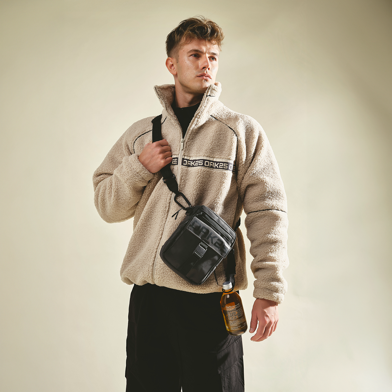Junge mit beiger Fleecejacke trägt schwarze OAK25 Luminite Bauchtasche mit Flasche