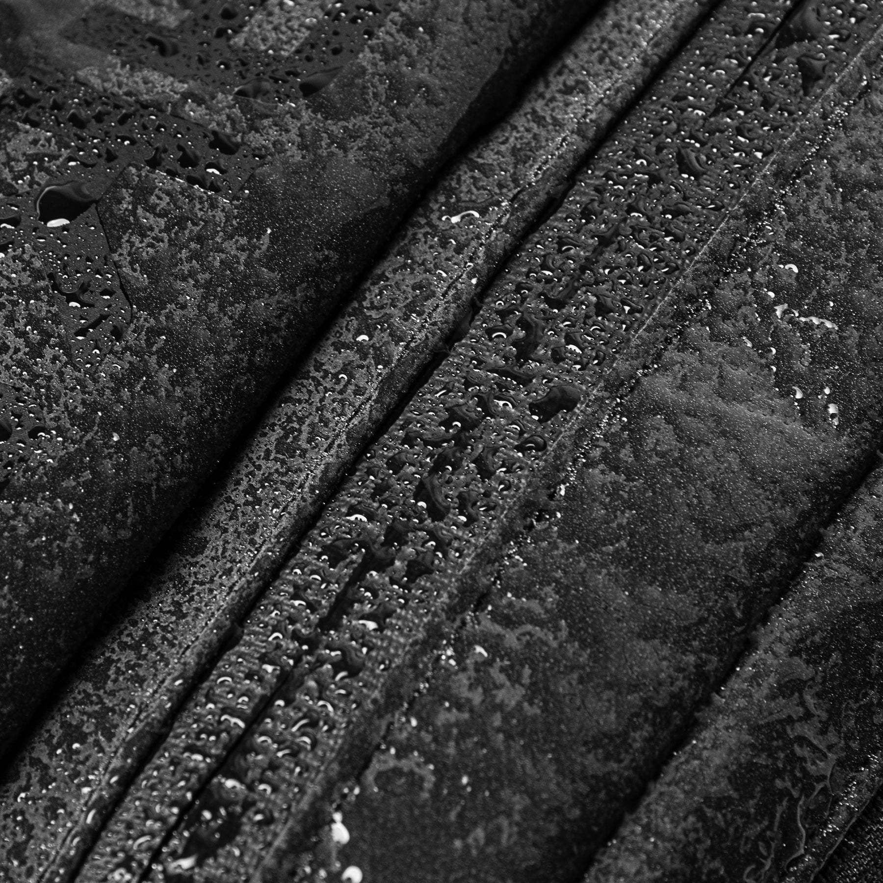 Nahaufnahme eines schwarzen, wasserdichten Reißverschlusses mit Wassertropfen