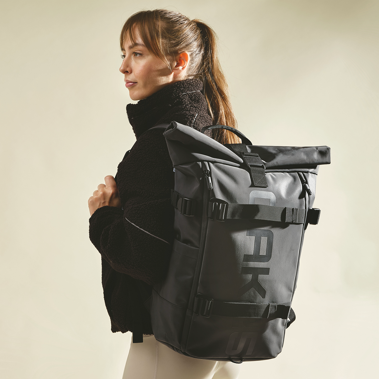 Frau trägt schwarzen OAK25 Luminite Rolltop Rucksack mit reflektierenden Elementen