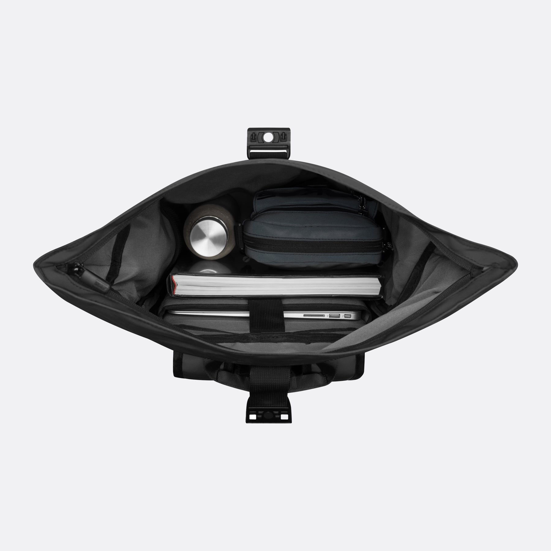 Geöffneter schwarzer Luminite Rolltop Rucksack mit großem Hauptfach, gefüllt mit Laptop, Buch, Flasche und Tasche