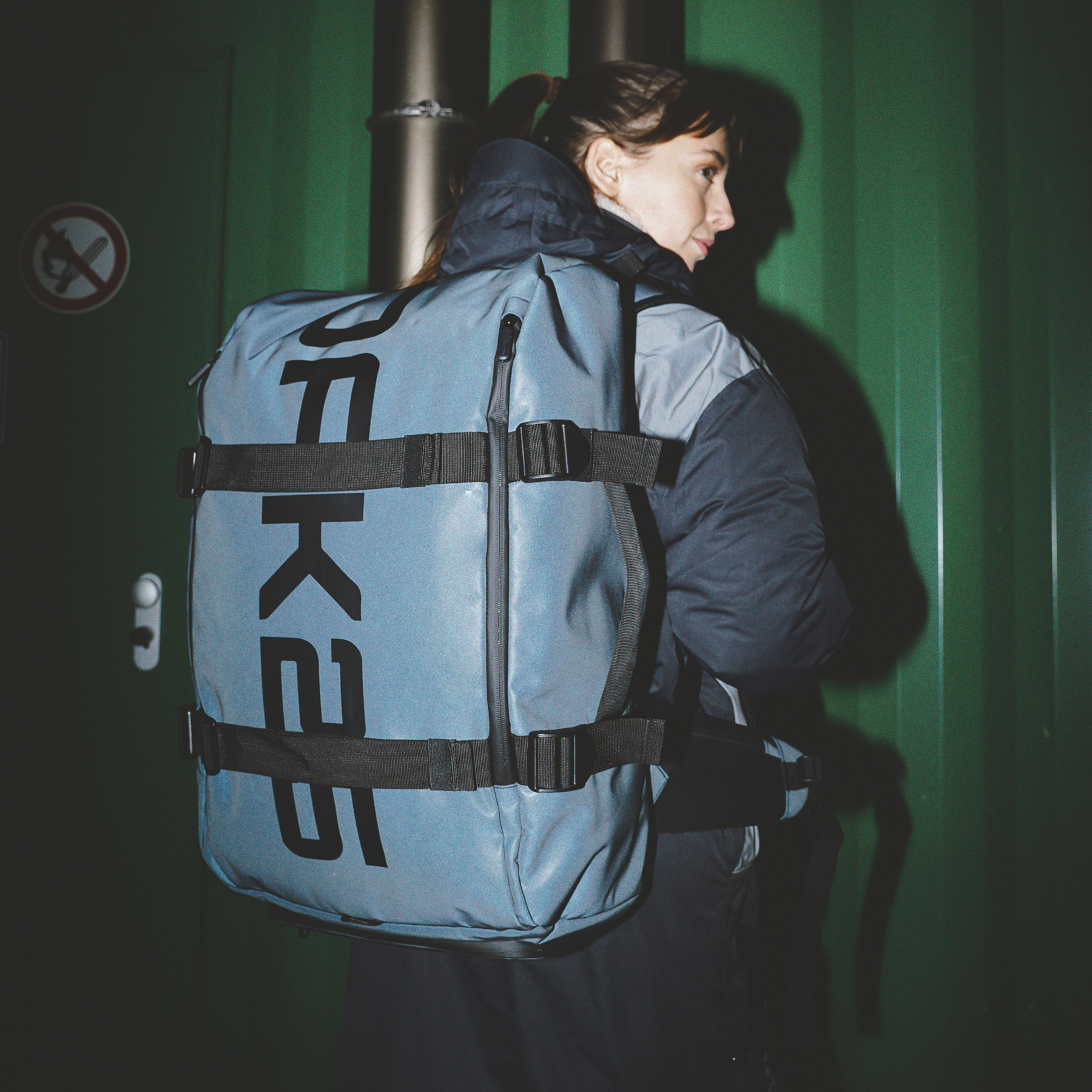 Frau trägt schwarzen Luminite Traveller Damenrucksack mit markantem Logo und verstellbaren Riemen