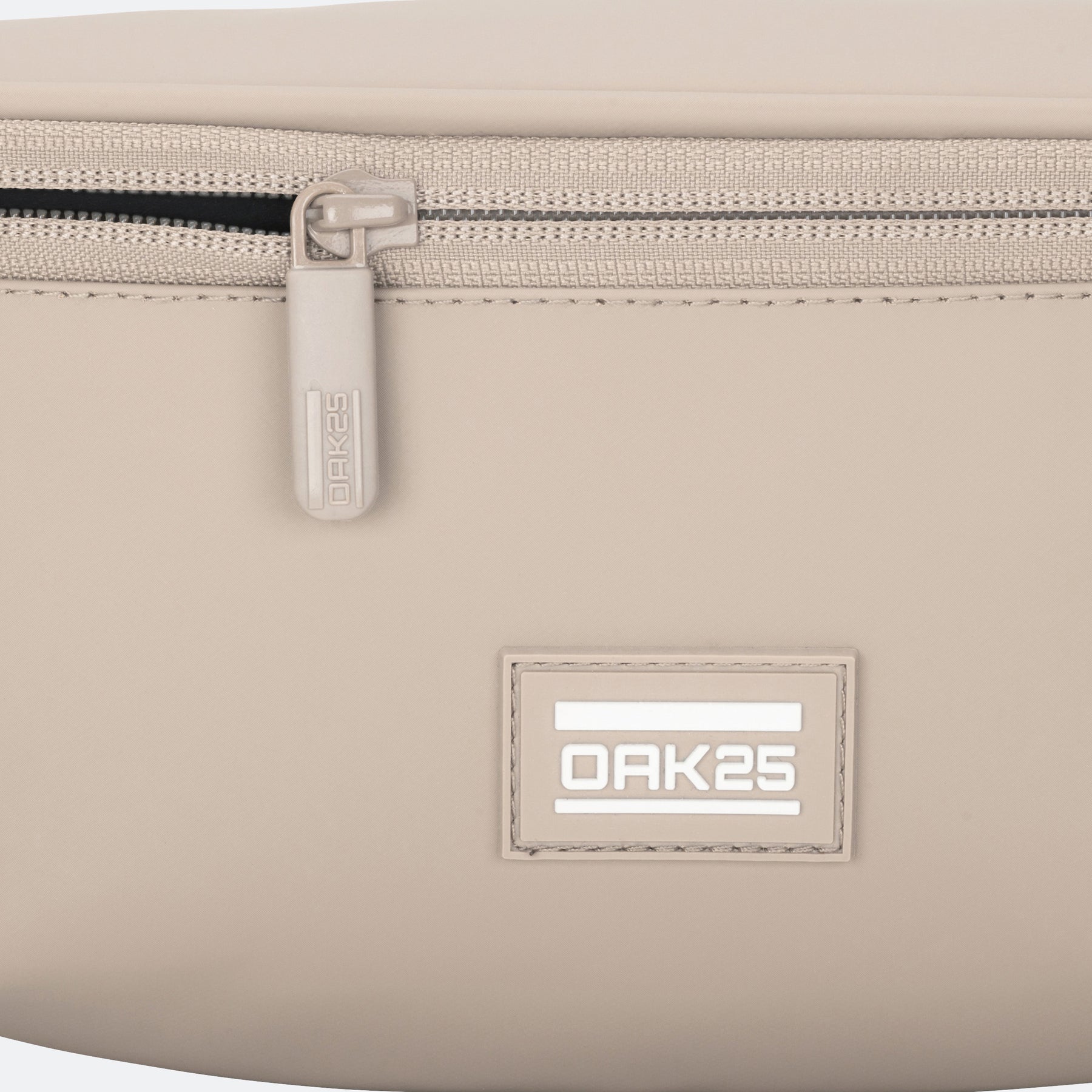 Nahaufnahme eines sandfarbenen OAK25-Alltags-Slingbags mit Reißverschluss und Logo