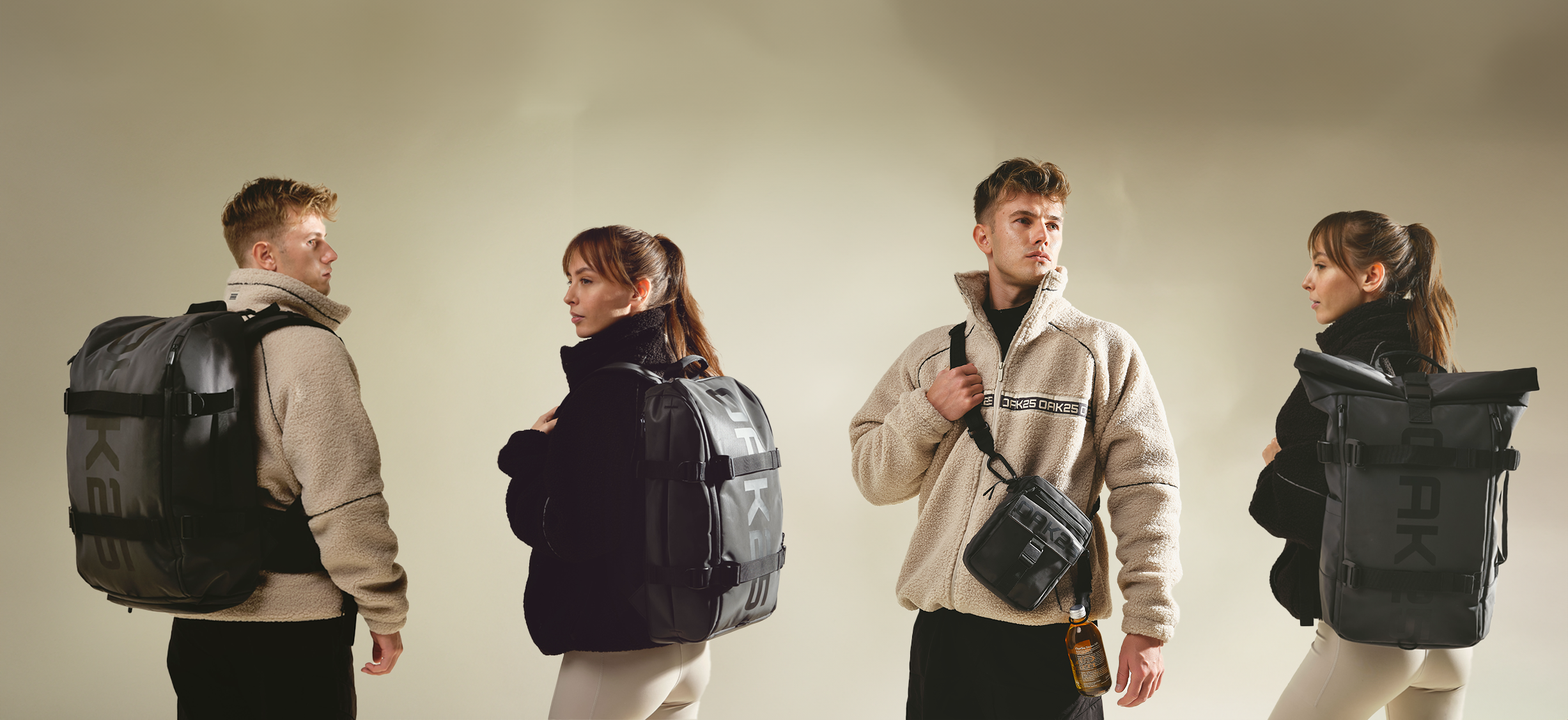 Vier Personen tragen die OAK25 Luminite Kollektion: zwei mit beigen Fleecejacken und schwarzen Rucksäcken, zwei mit schwarzen Jacken, eine mit schwarzem Rucksack und eine mit schwarzer Umhängetasche und Flasche